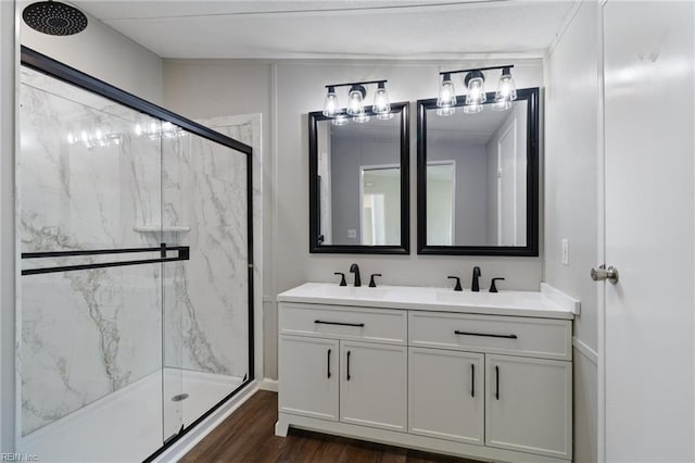 full bath featuring a sink, a marble finish shower, double vanity, and wood finished floors