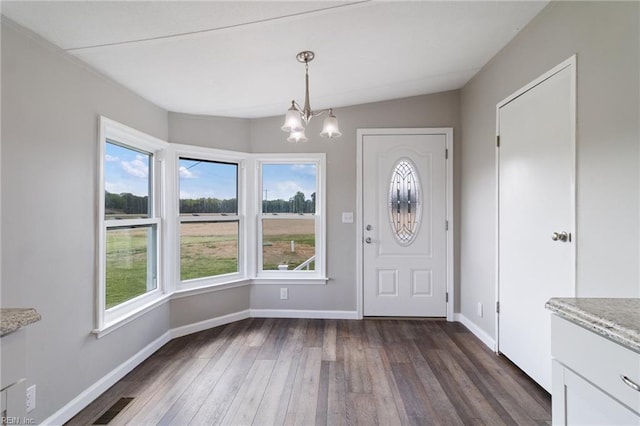 foyer with baseboards, an inviting chandelier, a healthy amount of sunlight, and dark wood-type flooring