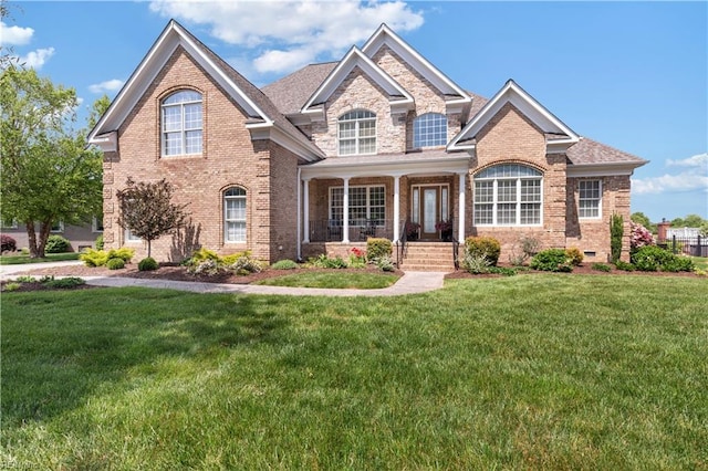 view of front of property with brick siding, a front yard, and a porch