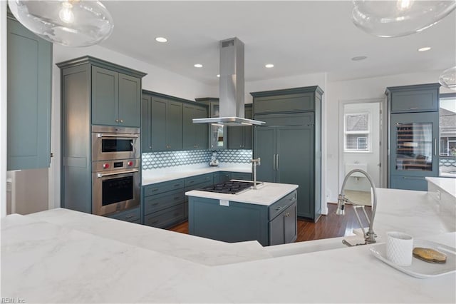 kitchen featuring appliances with stainless steel finishes, beverage cooler, island range hood, tasteful backsplash, and dark wood-type flooring