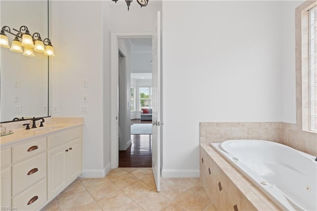ensuite bathroom featuring tiled tub, vanity, baseboards, tile patterned floors, and ensuite bath