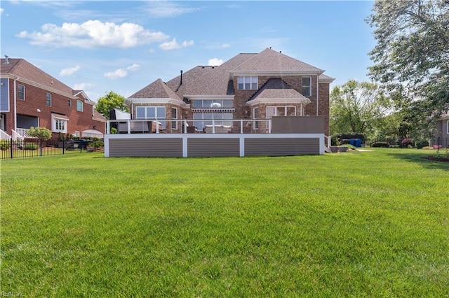 back of property featuring fence, a lawn, and brick siding