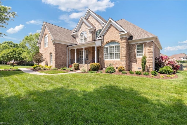 view of front of property with brick siding, a shingled roof, and a front lawn