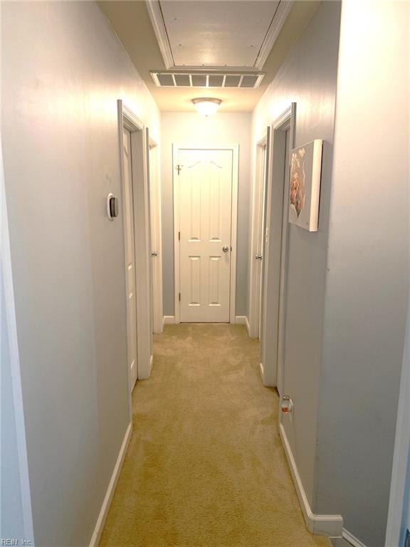 corridor with light colored carpet, baseboards, visible vents, and attic access