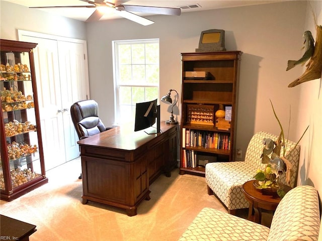 office area featuring a ceiling fan, visible vents, and light carpet