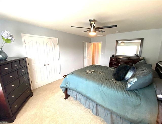 bedroom with a ceiling fan, light carpet, and a closet
