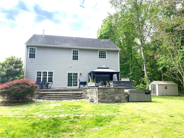 rear view of house featuring a gazebo, a lawn, a shed, and an outbuilding