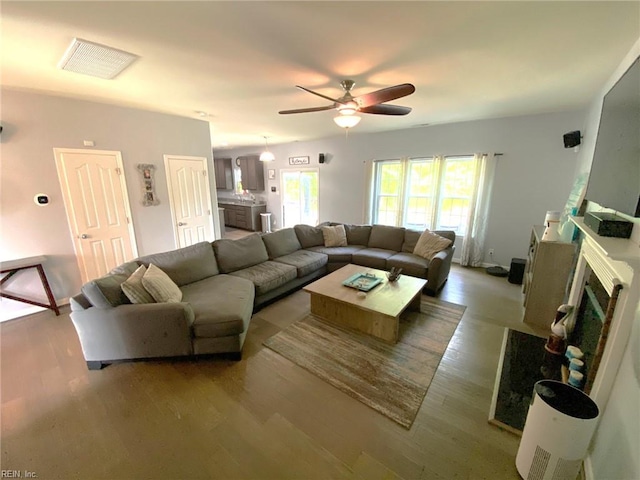 living area with baseboards, ceiling fan, visible vents, and wood finished floors