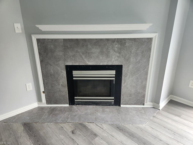 details featuring baseboards, a fireplace, and wood finished floors