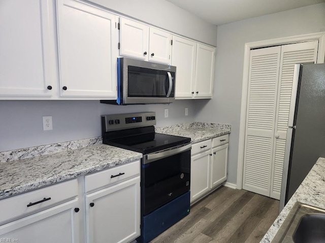kitchen featuring appliances with stainless steel finishes, white cabinets, light stone counters, and dark wood-type flooring