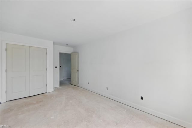 unfurnished bedroom with baseboards, a closet, and concrete flooring