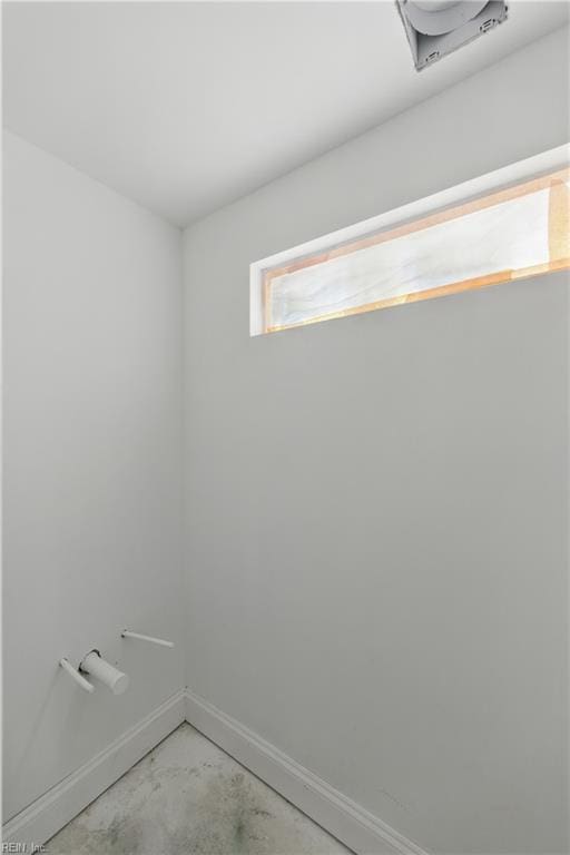 spare room featuring unfinished concrete floors and baseboards