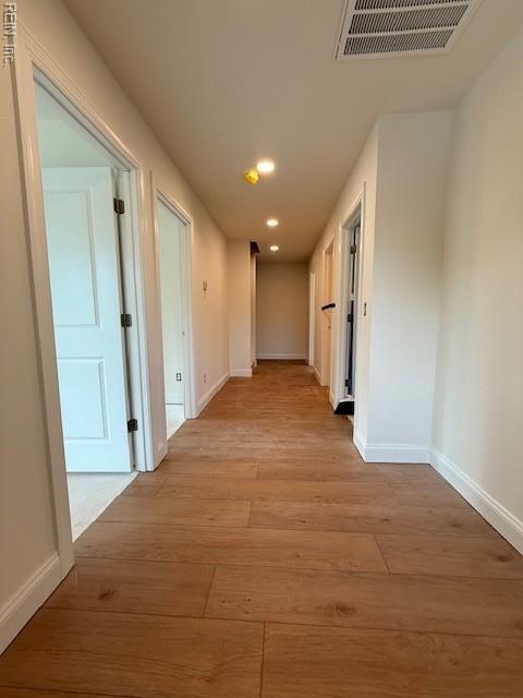hallway featuring baseboards, recessed lighting, and light wood-type flooring