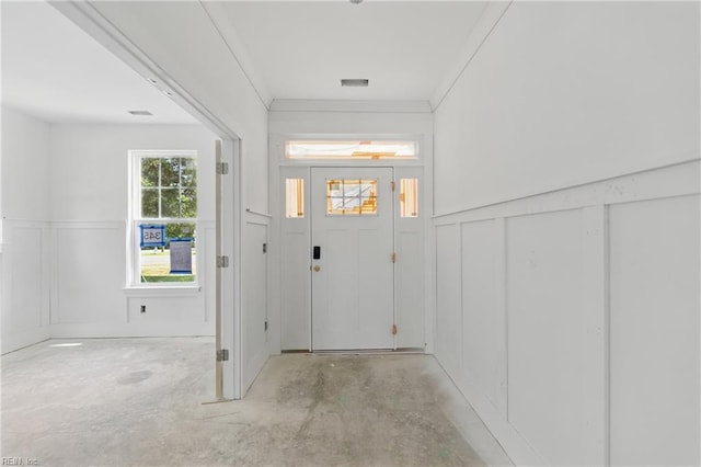 foyer featuring a decorative wall, wainscoting, and unfinished concrete flooring