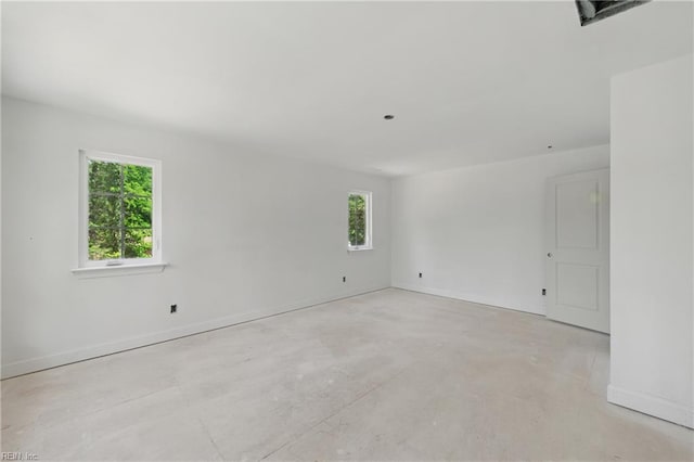 unfurnished room with unfinished concrete floors and baseboards