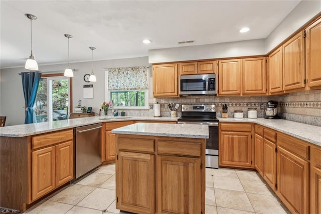 kitchen with appliances with stainless steel finishes, ornamental molding, backsplash, visible vents, and a kitchen island