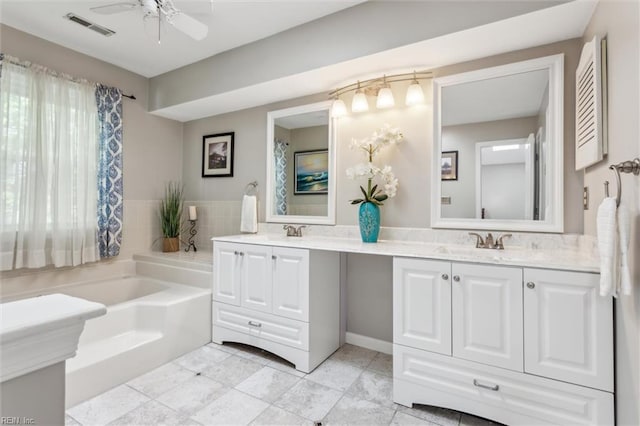 full bath featuring a sink, double vanity, a ceiling fan, visible vents, and a garden tub