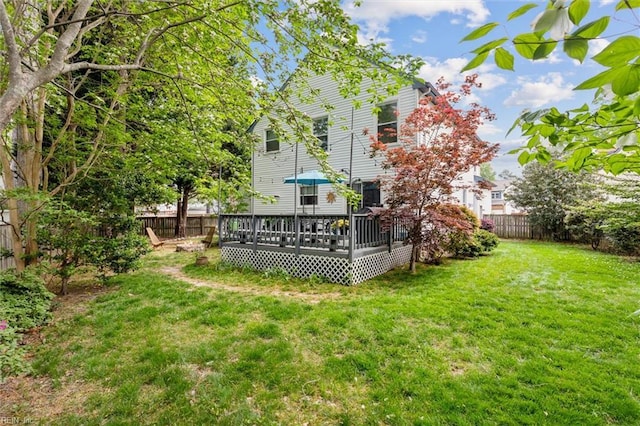back of house with a fenced backyard, a yard, and a deck