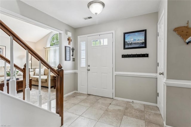 foyer entrance with stairway, baseboards, and visible vents