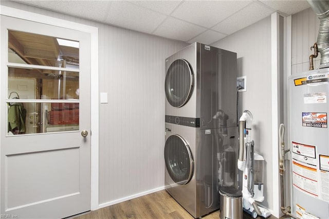 laundry room with stacked washing maching and dryer, gas water heater, laundry area, and wood finished floors