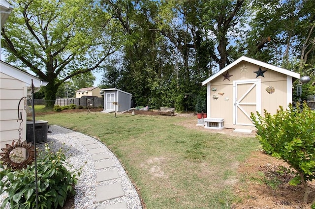 view of yard with a storage shed, fence, an outbuilding, and central AC unit