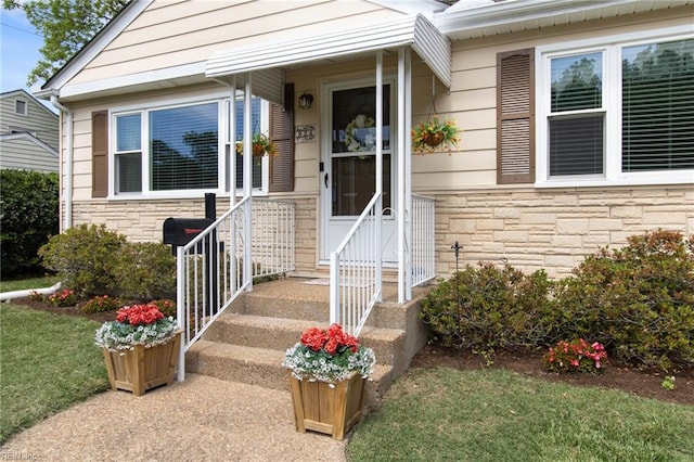 entrance to property with a lawn and stone siding