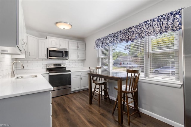 kitchen featuring dark wood-style floors, light countertops, tasteful backsplash, a sink, and appliances with stainless steel finishes