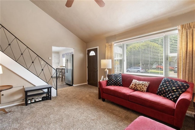 carpeted living room with stairs, a ceiling fan, baseboards, and vaulted ceiling
