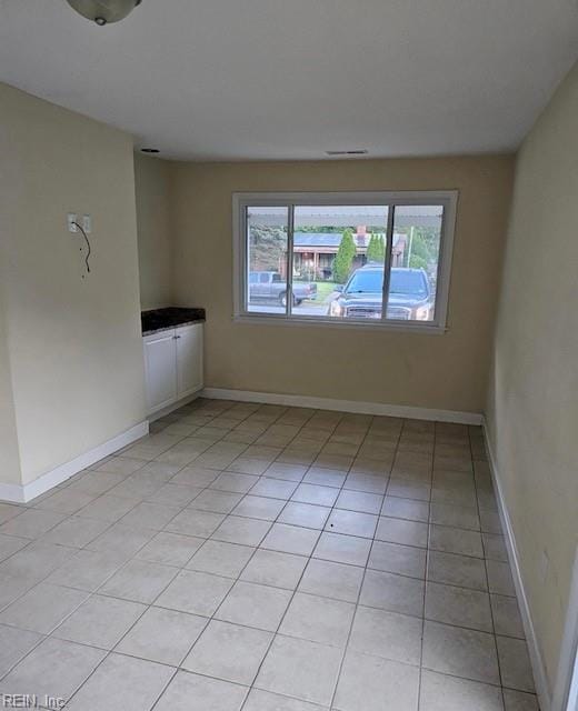 empty room featuring light tile patterned floors and baseboards