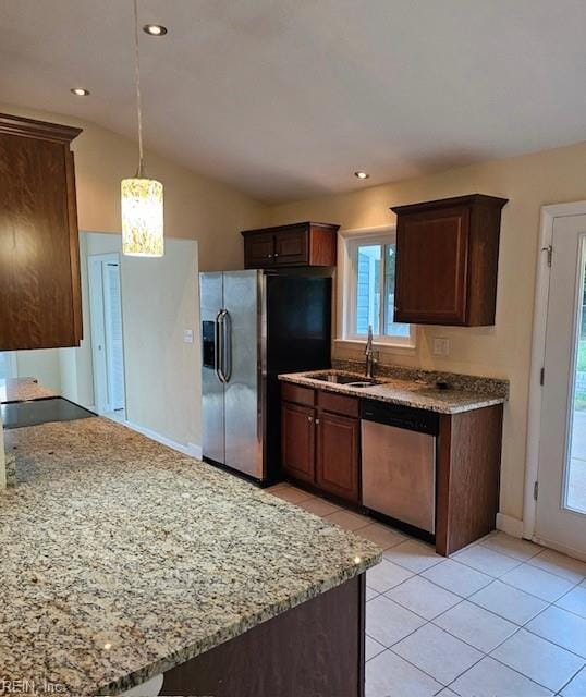 kitchen with a sink, light stone counters, light tile patterned floors, and stainless steel appliances