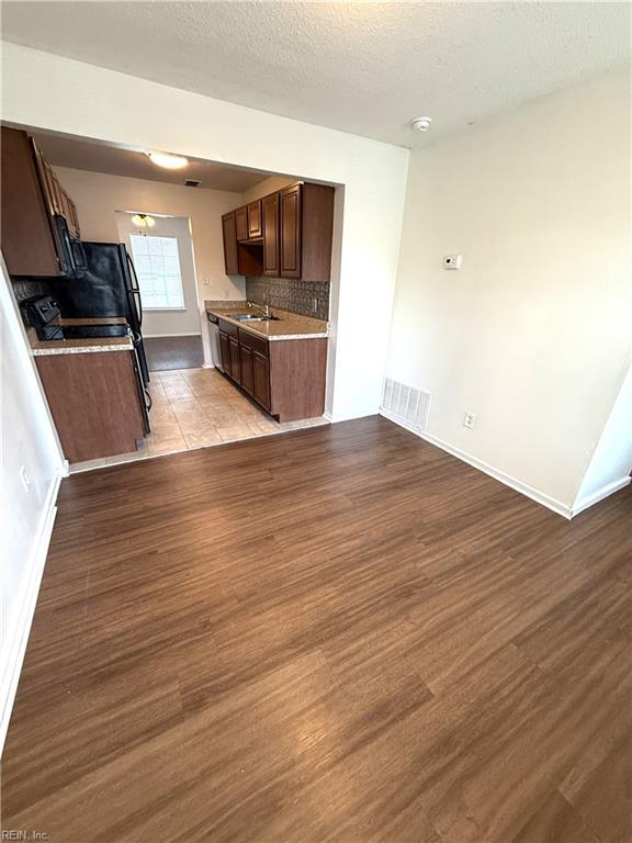 3703 Sylvan Ln, Virginia Beach, VA 23453 - kitchen featuring wood finished floors, light countertops, baseboards, dark brown cabinetry, and a textured ceiling