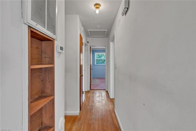 corridor featuring baseboards, attic access, and light wood-type flooring