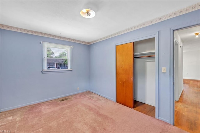 unfurnished bedroom featuring carpet floors, baseboards, visible vents, and a closet