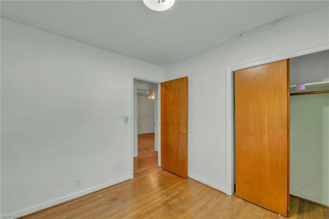 unfurnished bedroom with baseboards, wood finished floors, and a closet