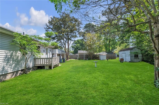 view of yard featuring a storage unit, an outdoor structure, fence, and a deck