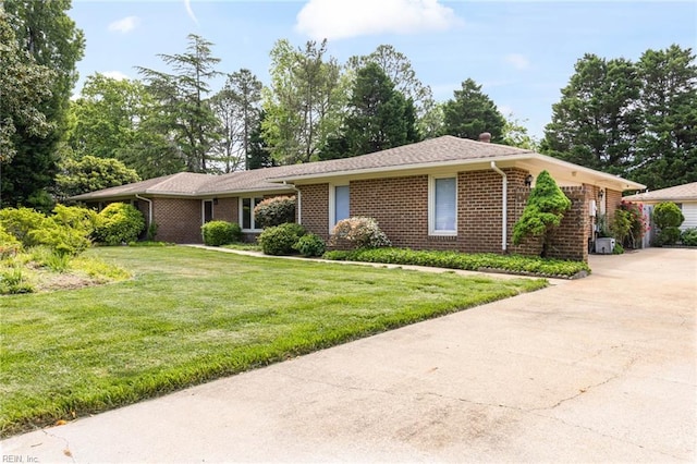 single story home featuring driveway, a front lawn, and brick siding