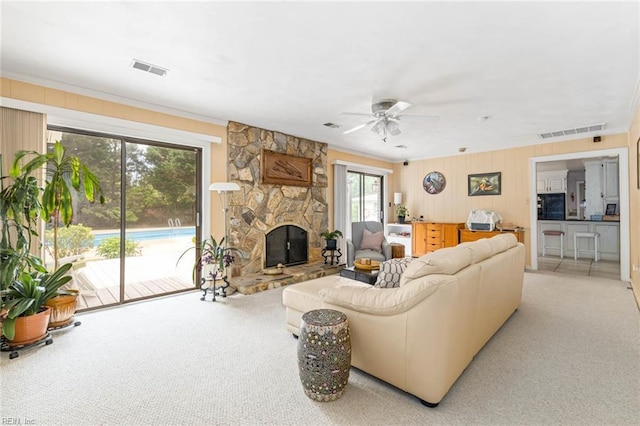 living room with a ceiling fan, light colored carpet, visible vents, and a fireplace