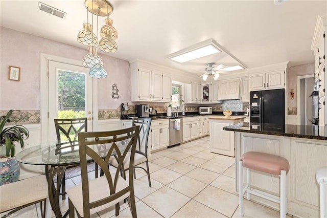 kitchen with stainless steel dishwasher, ceiling fan, white microwave, light tile patterned floors, and black fridge