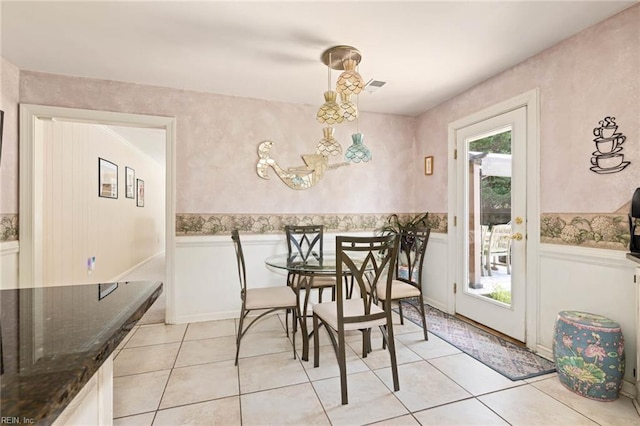 dining space featuring wainscoting, light tile patterned floors, and a chandelier