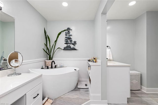 full bath with a wainscoted wall, a soaking tub, and vanity