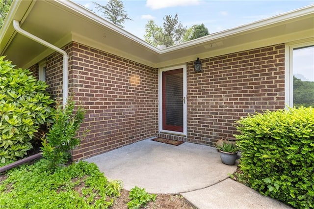 entrance to property with brick siding and a patio area