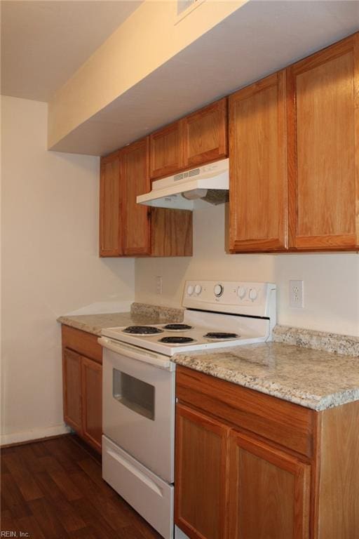 kitchen featuring dark wood-style flooring, electric range, brown cabinets, baseboards, and under cabinet range hood