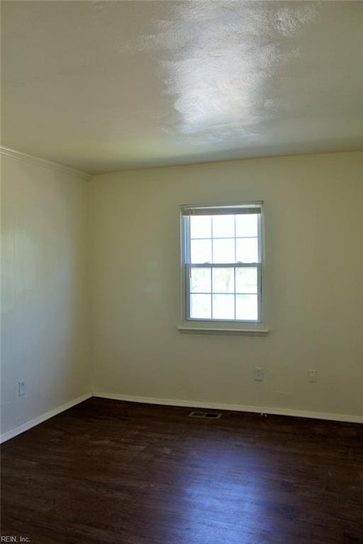 spare room featuring baseboards, visible vents, and wood finished floors