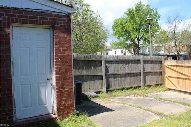 property entrance featuring brick siding, fence, and central air condition unit