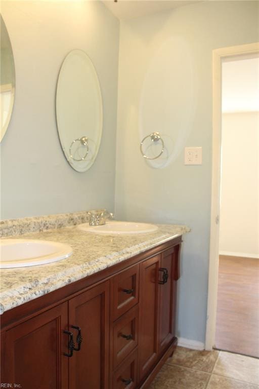 full bath featuring a sink, baseboards, and double vanity