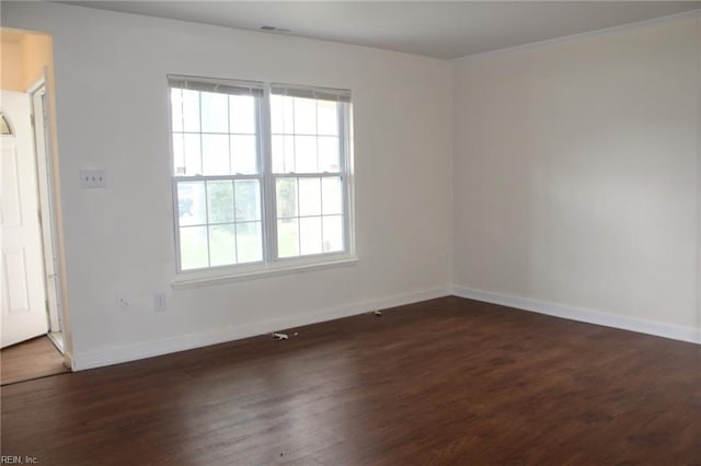 empty room with dark wood-style flooring, baseboards, visible vents, and plenty of natural light