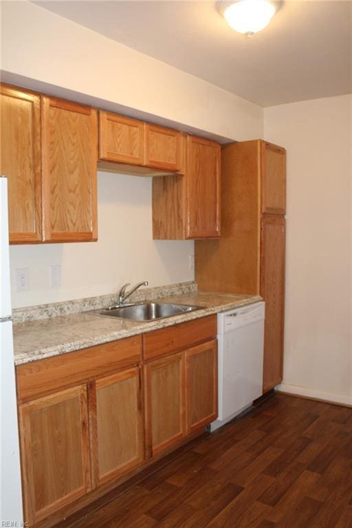 kitchen featuring white appliances, brown cabinets, dark wood finished floors, and a sink