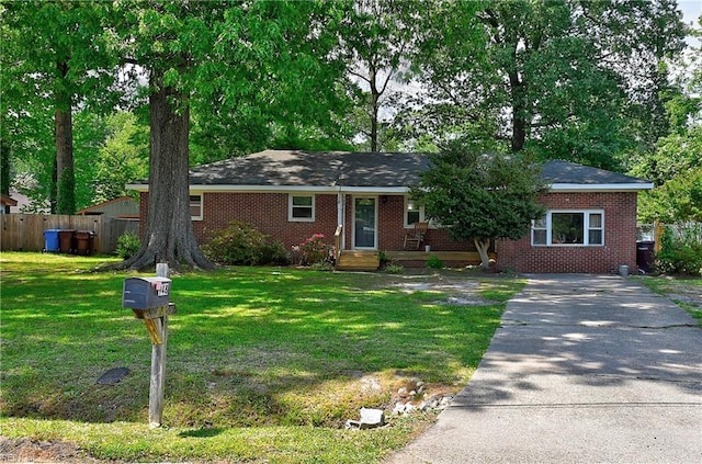 ranch-style home featuring brick siding, fence, and a front yard