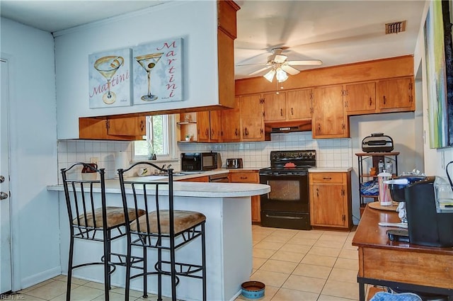 kitchen with a peninsula, ceiling fan, brown cabinetry, and black appliances