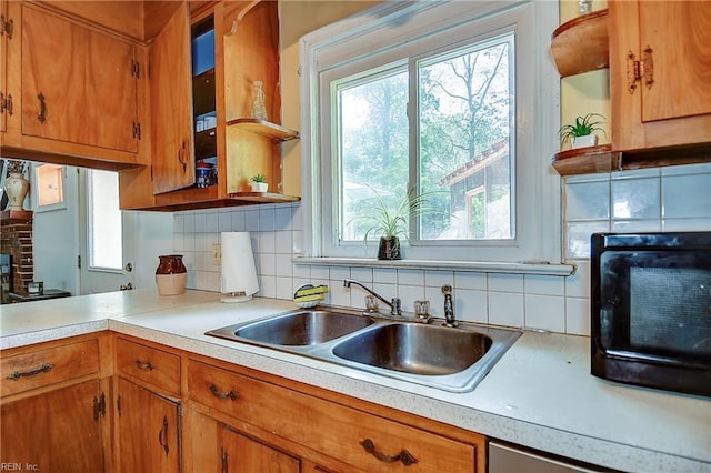 kitchen with backsplash, open shelves, brown cabinets, a sink, and light countertops